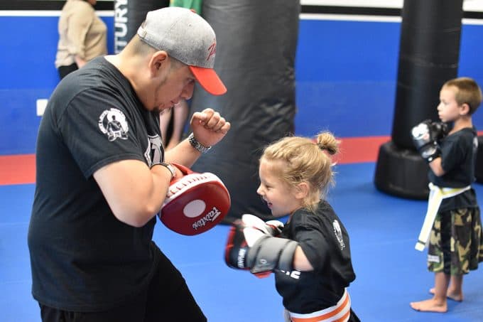 Coach holding focus mitts for a young student at Next Level Martial Arts