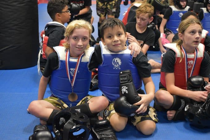 Kids holding tournament medals at Next Level Martial Arts